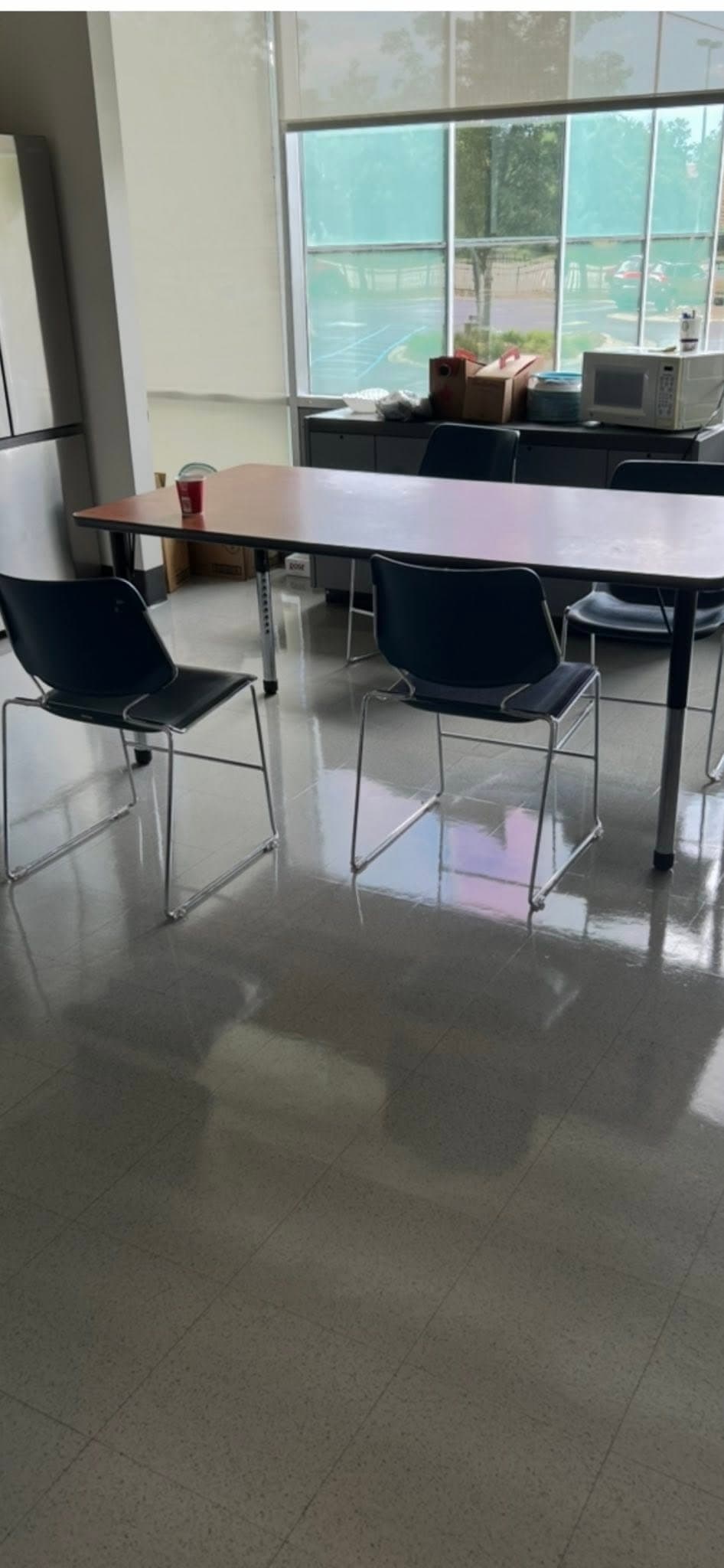 A high-gloss office break-area floor reflecting the window line after refinishing.