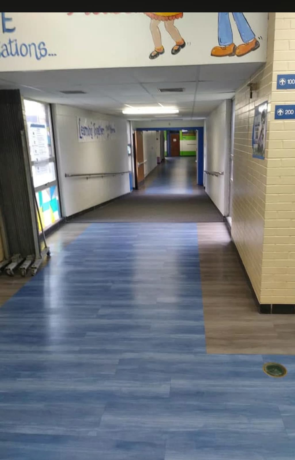 A school corridor with its vinyl plank floor cleaned and the whole run left clear.